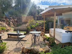 een tuin met een tafel en een bad bij בית גלילי מול היער in ‘Ein Ya‘aqov