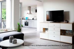 a living room with a tv on a white dresser at Ferienhaus Strandläufer in Langballig