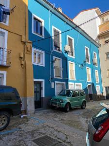 een groene auto geparkeerd voor een blauw gebouw bij Cuencaloft Apartamentos el Nazareno in Cuenca