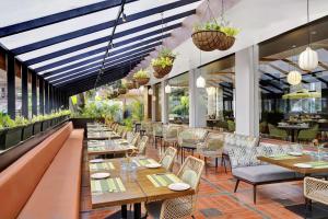 a restaurant with tables and chairs and windows at Radisson Resort Goa Baga in Baga