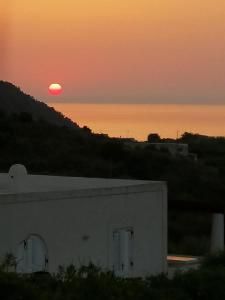 einen Sonnenuntergang über dem Meer und ein weißes Gebäude in der Unterkunft Casa Mariva in Lipari