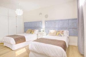 2 camas en un dormitorio con paredes blancas y suelo de madera en La Favorita preciosa villa con piscina privada, en Corralejo