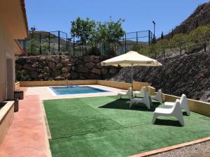 a swimming pool with two chairs and an umbrella at Hostel Águilas Isla del Fraile in Águilas
