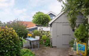 un jardín con un cobertizo gris y una mesa en Uit Alle Windstreken, en Hindeloopen