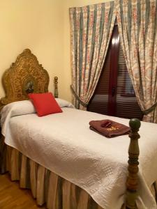 1 dormitorio con cama con almohada roja y ventana en Naturaleza Soria Parques Naturales, en San Esteban de Gormaz