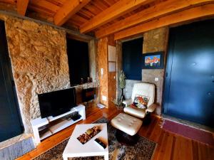 a living room with a stone wall with a tv and chairs at Casa de campo com vista a montanha in Sever do Vouga