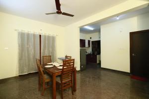 a dining room with a table and chairs and a ceiling fan at Tranquil orchid serviced Apartment in Bangalore