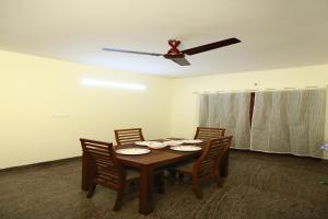 a dining room table with four chairs and a ceiling fan at Tranquil orchid serviced Apartment in Bangalore
