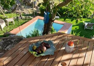 une assiette de fruits sur une table à côté d'une piscine dans l'établissement CASA DA VIZINHA, QUINTA DAS MEMÓRIAS, à Santo António das Areias