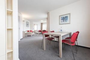 uma sala de jantar com uma mesa e cadeiras vermelhas em EMA House Serviced Apartments Aussersihl em Zürich