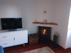 a living room with a tv and a fireplace at CASA DA VIZINHA, QUINTA DAS MEMÓRIAS in Santo António das Areias