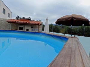 a swimming pool with an umbrella and a house at Casa Monte de Baixo in Pousadela