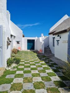 a stone walkway between two white buildings at Casa Pescador Beach House in Struisbaai