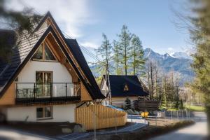 ein Haus mit Balkon und Bergen im Hintergrund in der Unterkunft TatryTop Apartamenty Alpejski SPA in Kościelisko