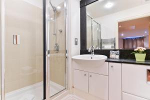 a white bathroom with a sink and a shower at Paddington Gardens in London