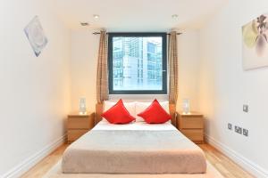 Un dormitorio con una cama con almohadas rojas y una ventana en Paddington Gardens en Londres