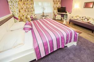ein Schlafzimmer mit einem Bett mit einer gestreiften Decke in der Unterkunft Hotel am Hopfensee in Füssen