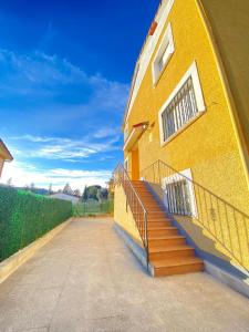 a yellow building with a staircase next to a stair case at S&H El Caprichoso in Valdemaqueda