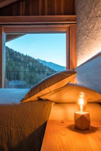 a candle sitting on top of a bed with a window at Chalet Noèr in Ledro