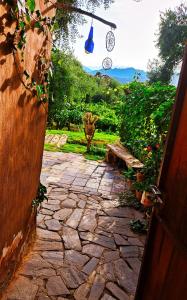 a stone walkway leading to a garden with a statue at Munay EcoHostal - Cabañas de Adobe in Tinogasta