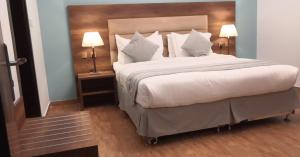 a bedroom with a large white bed with two lamps at منتجع فيوري - الهدا in Taif