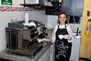 a woman standing in a kitchen holding two cups at Hotel Aroma del Bosque Posada Cafe in Tunja
