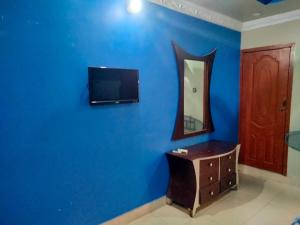 a room with a blue wall with a tv and a mirror at Entire Home's for family in Karachi