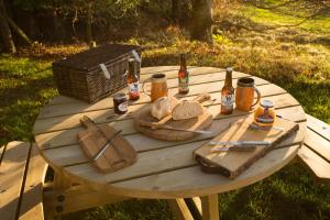 een houten picknicktafel met brood en flessen bier bij The White Cottage in Elgin