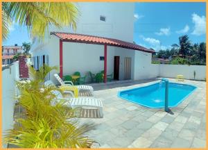 a patio with a pool and chairs and a house at Espaçosos Aptos em Porto de Galinhas - Condominio com Piscina - Perto de tudo! in Porto De Galinhas +19 photos