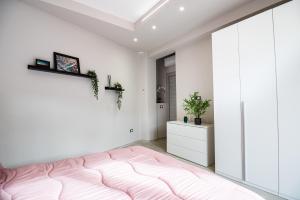 a bedroom with a pink bed and white walls at CDO Apartment in Capo dʼOrlando