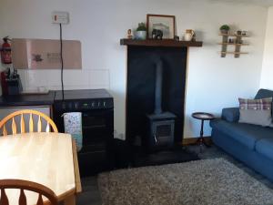 a living room with a blue couch and a stove at Self-catering Cottage at Benview in Staffin
