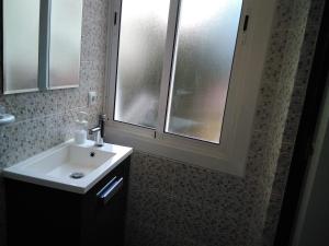 a bathroom with a white sink and two windows at Coqueto apartamento in Barcelona