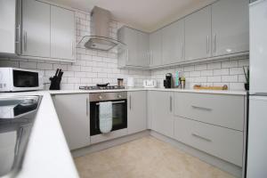 a white kitchen with white appliances and white cabinets at Family Home in the Charming Coastal Town of Barry in Barry