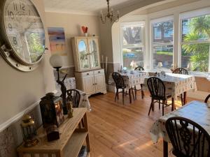 a dining room with tables and chairs and a clock on the wall at San Brelade in Paignton