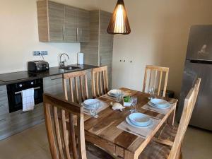 una cocina con mesa de madera y sillas con platos y vasos. en Spanish Water View Apartment C1, en Willemstad