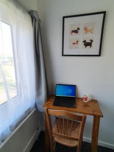 a laptop computer sitting on a wooden table next to a window at Rabbit Haven - 4 minutes from Bicester Village! in Bicester