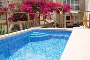 una piscina con agua azul y flores rosas en CASA OASIS en Calella