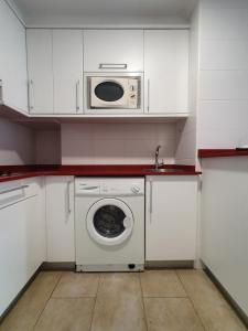 a kitchen with a washing machine and a microwave at Playa Colina in Argoños