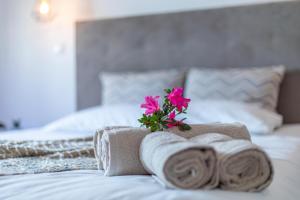ein Schlafzimmer mit Handtüchern und einer Blume auf dem Bett in der Unterkunft Carvão Pdl Inn in Arrifes