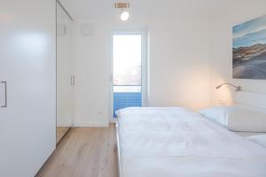 a white bedroom with two beds and a window at Verpuusten in Husum