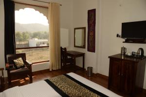 a bedroom with a bed and a window and a desk at Omak Tiger Seven in Sawāi Mādhopur