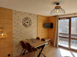 une salle à manger avec une table et une horloge murale dans l'établissement Studio Le Flocon entièrement rénové, aux Orres