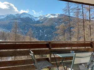 a table and chairs on a balcony with mountains at Studio Le Flocon entièrement rénové in Les Orres