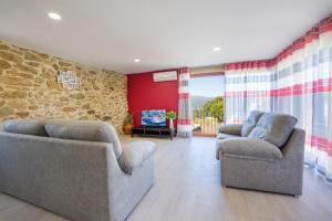 a living room with two chairs and a stone wall at Casa das Eiras 