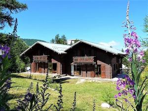 a large wooden house in a field with purple flowers at CASA Les Heureux Magnifique CHALET 6 chambres à RISOUL in Risoul