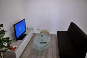 uma sala de estar com uma mesa de vidro e uma televisão em Apartamento DAVI no Funchal