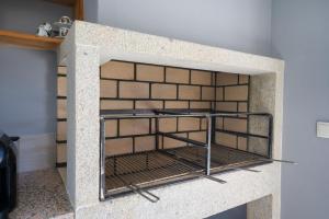 a brick fireplace with a metal grate in it at Casa das Eiras 