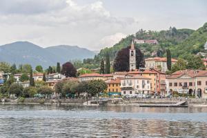 una città vicino a un corpo d'acqua con una torre dell'orologio di Appartamento Ormeggio Lago Maggiore a Laveno