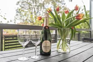 una bottiglia di champagne e due bicchieri di vino su un tavolo di legno di Appartamento Ormeggio Lago Maggiore a Laveno