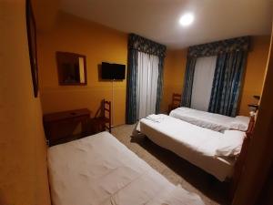 Una habitación de hotel con dos camas y un televisor. en Hotel Nuevo Lorenzo, en Salamanca